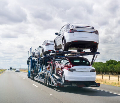 May 25, 2018 Bakersfield / CA / USA - Car transporter carries Tesla Model 3 new vehicles along the highway, back view of the trailer