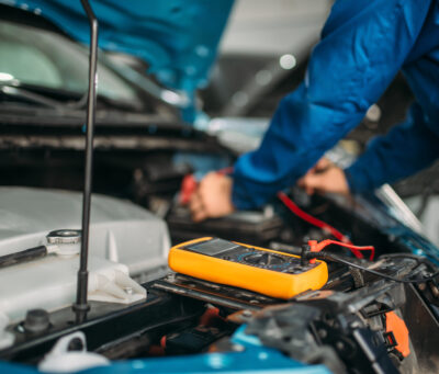 Car electrician checks the battery level Car electrician with multimeter checks the battery level. Auto-service, vehicle wiring diagnostic